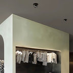 Clérachic two black adjustable downlights set into a dark ceiling above a boutique clothes rail with a strip light.