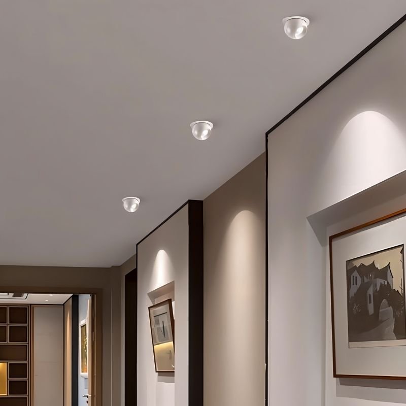 Clérachic row of white ball downlights along a corridor ceiling, each aimed to light a framed picture on the wall.