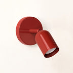 Red Clérachic wall light, its round backplate and tilted head in one glossy colour, shown on a pale cream wall.