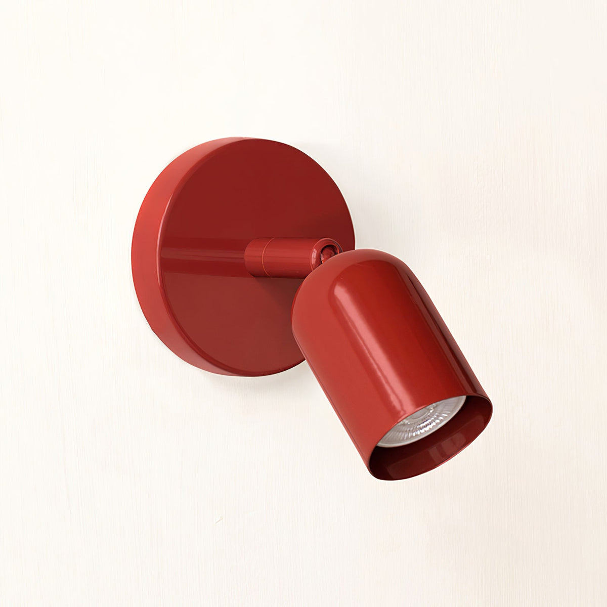 Red Clérachic wall light, its round backplate and tilted head in one glossy colour, shown on a pale cream wall.