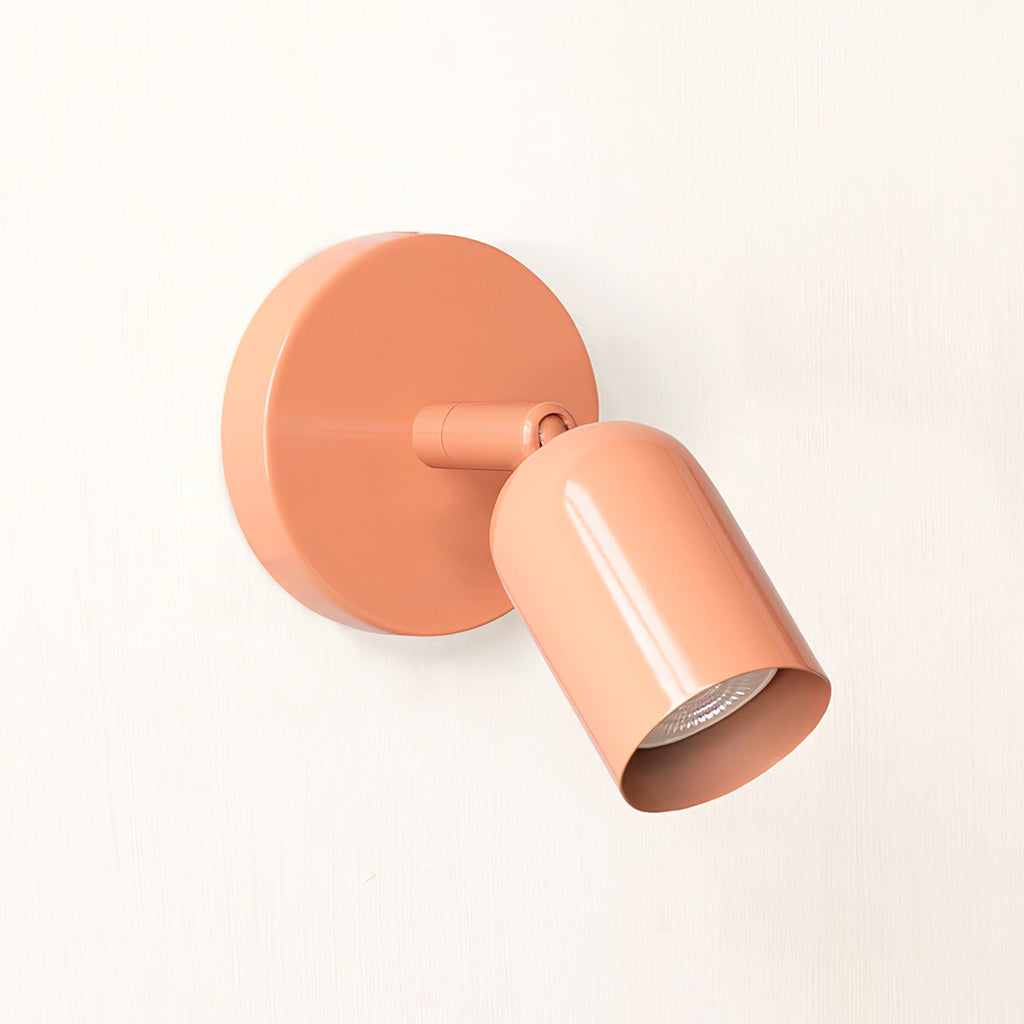 Pink Clérachic wall light angled to the right, its glossy head sharing the shade of the backplate, on a cream wall.