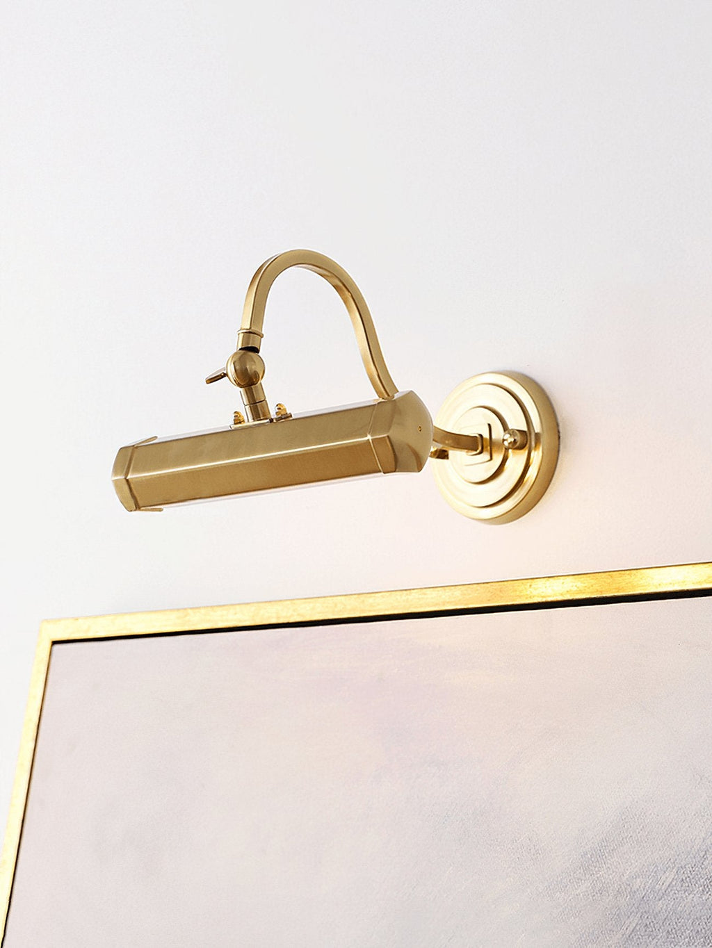 Above a gold-edged canvas, this gold Clérachic wall light glows softly from its round backplate and curved arm.