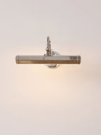 Chrome Clérachic wall light lit from within, throwing a warm glow across a peach-toned wall.