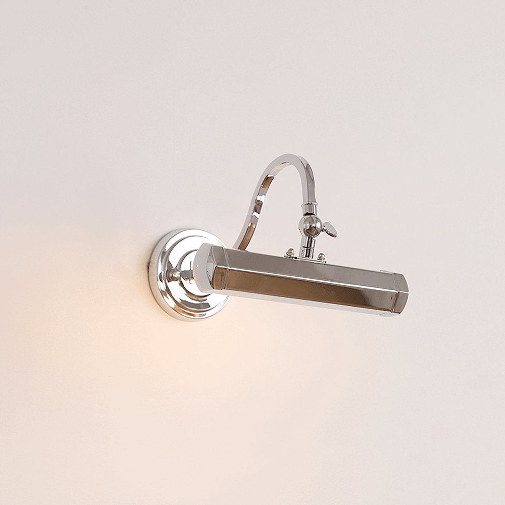 With its chrome shade turned sideways, this Clérachic wall light glows softly against a warm cream wall.