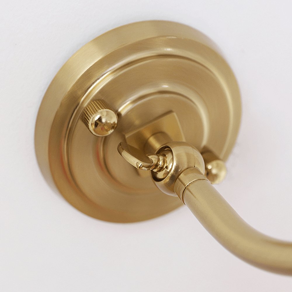 Close view of the round, stepped gold backplate and the arm joint on this Clérachic wall light.