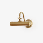 Gold Clérachic wall light with a curved arm and hexagonal shade, shown at a slight angle on a plain white background.