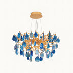 This Clérachic chandelier on a plain white backdrop, with blue agate slices hanging from a branching gold frame and a round gold canopy.