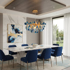 Blue agate Clérachic chandelier above a white marble dining table with navy chairs, with a seaside view through the glass doors.