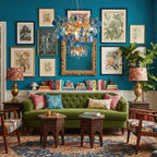 Clérachic agate chandelier over a bold living room with a teal wall of framed prints and a green velvet sofa.