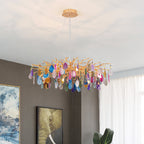 Multicolour agate Clérachic chandelier in a room with a grey wall and framed art, with sheer curtains to the right.