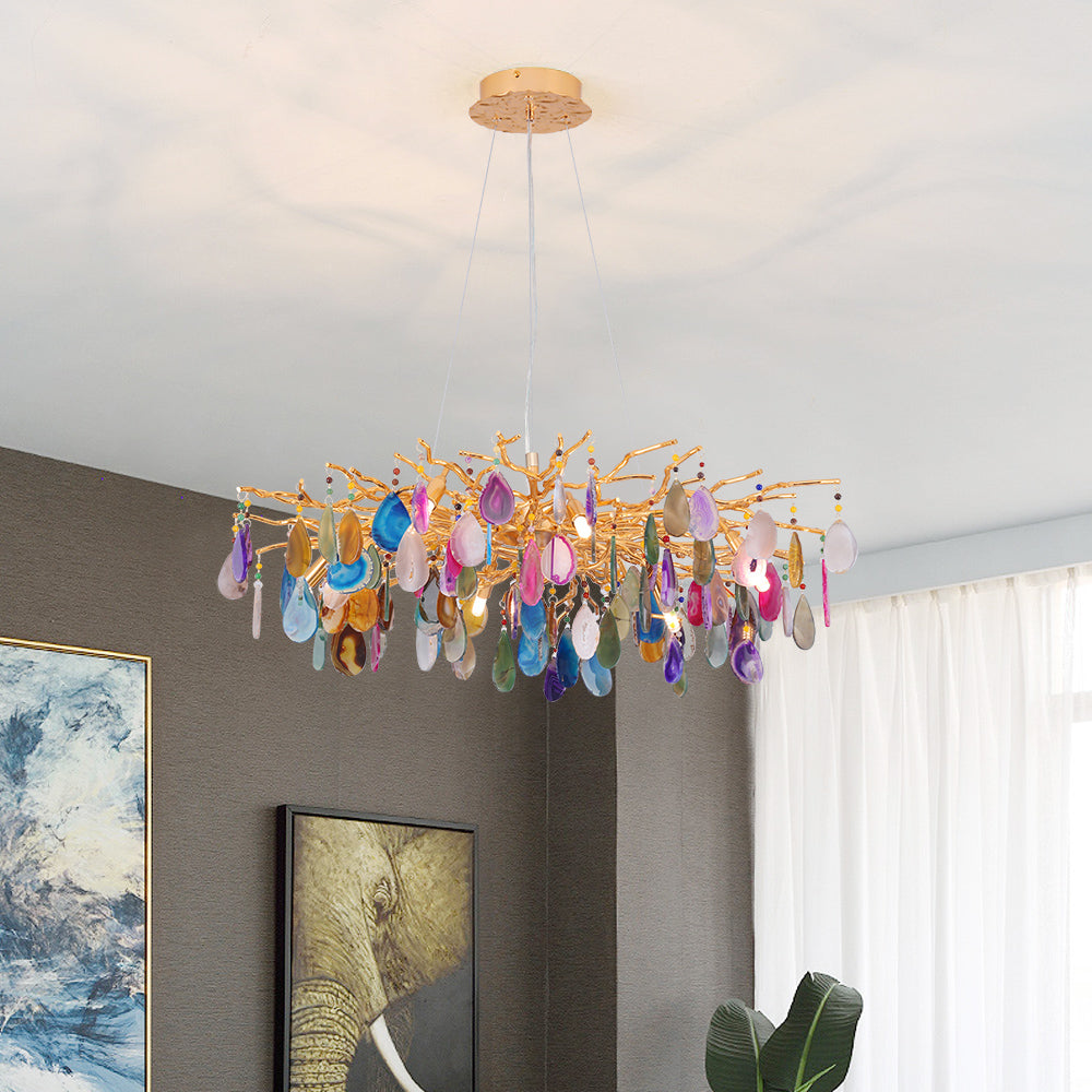 Multicolour agate Clérachic chandelier in a room with a grey wall and framed art, with sheer curtains to the right.