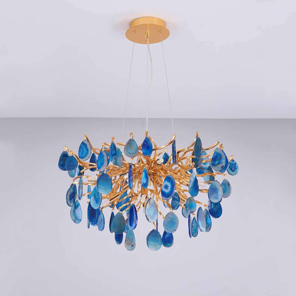 Unlit blue agate Clérachic chandelier hanging from a gold canopy, with the stone slices in shades from navy to pale sky blue.
