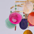 Close view of pink, teal, purple and orange agate discs hanging from gold branches on this Clérachic chandelier.