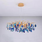 Blue agate Clérachic chandelier on a pale grey backdrop, with slices from navy to sky blue on a wide gold frame.