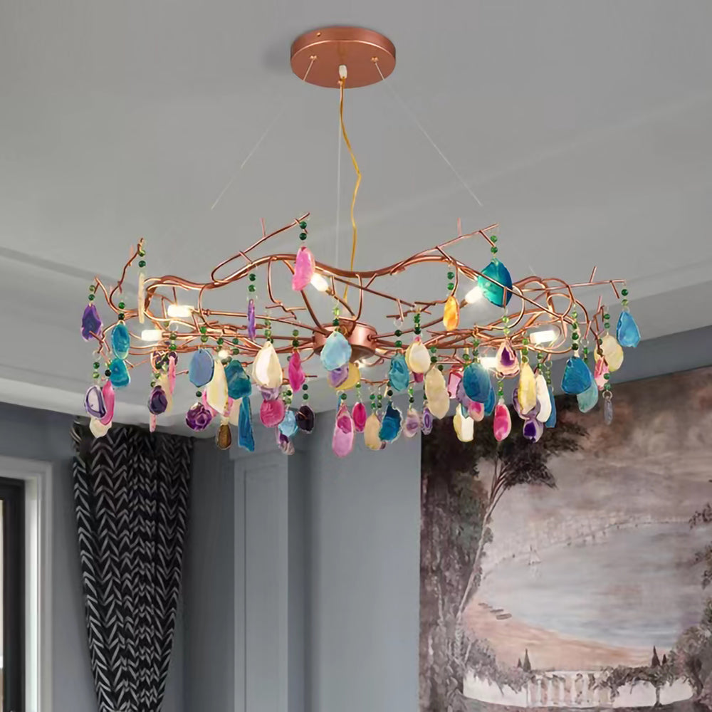 Close view of the stone slices and the rose-gold branches on this Clérachic agate chandelier, against a grey wall and a mural.