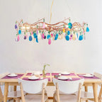 Clérachic agate chandelier of mixed pink, blue and gold slices above a light wooden dining table with white chairs.