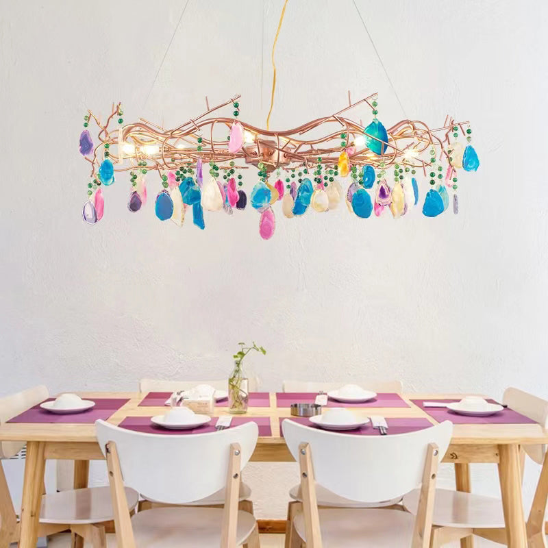 Clérachic agate chandelier of mixed pink, blue and gold slices above a light wooden dining table with white chairs.