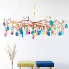 Clérachic agate chandelier with multicolour stone slices, hung in a bright room above two small stools and a sprig of dry stems.