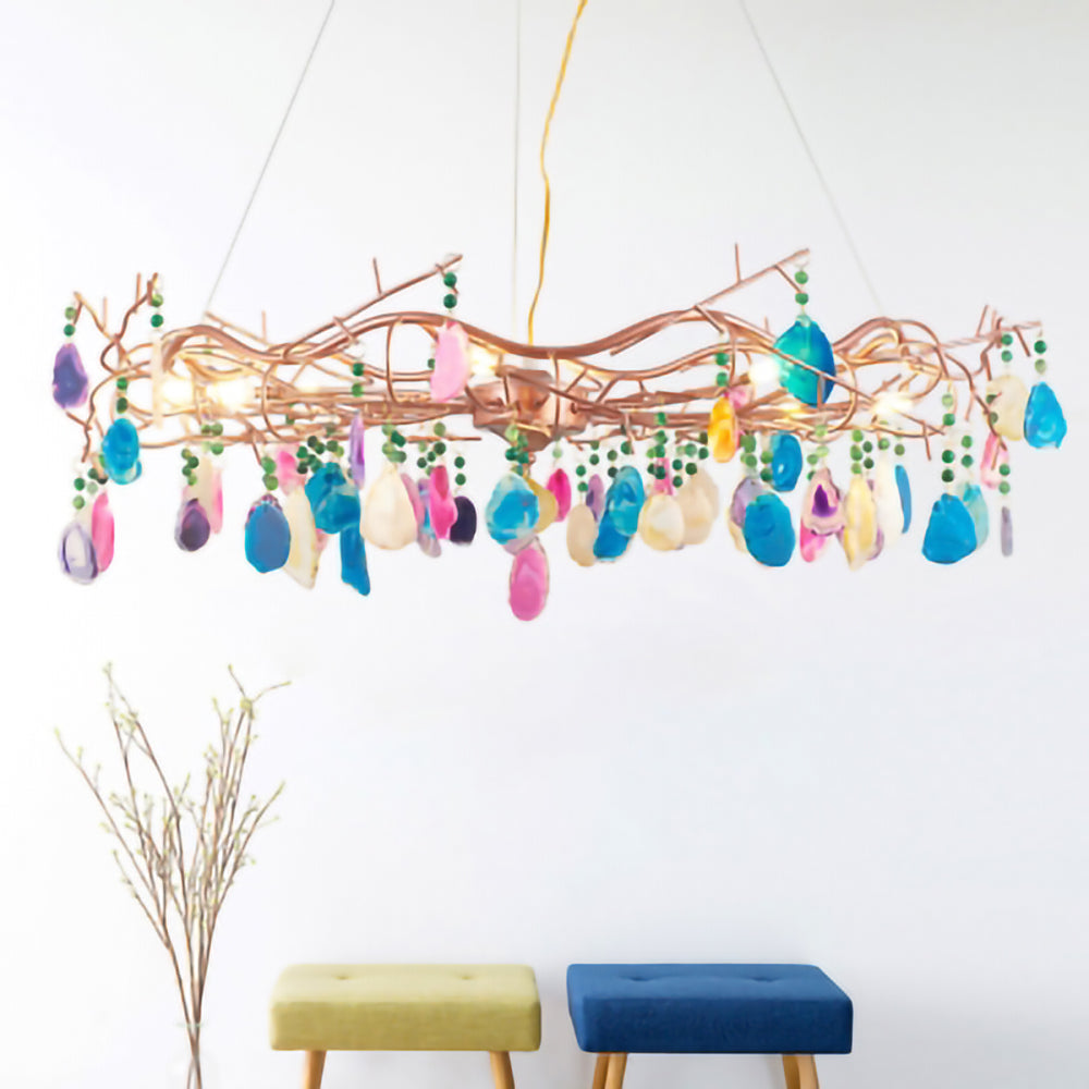 Clérachic agate chandelier with multicolour stone slices, hung in a bright room above two small stools and a sprig of dry stems.