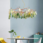 Green-slice Clérachic agate chandelier above a small round table with a lemon bowl, in front of a blue-grey wall.