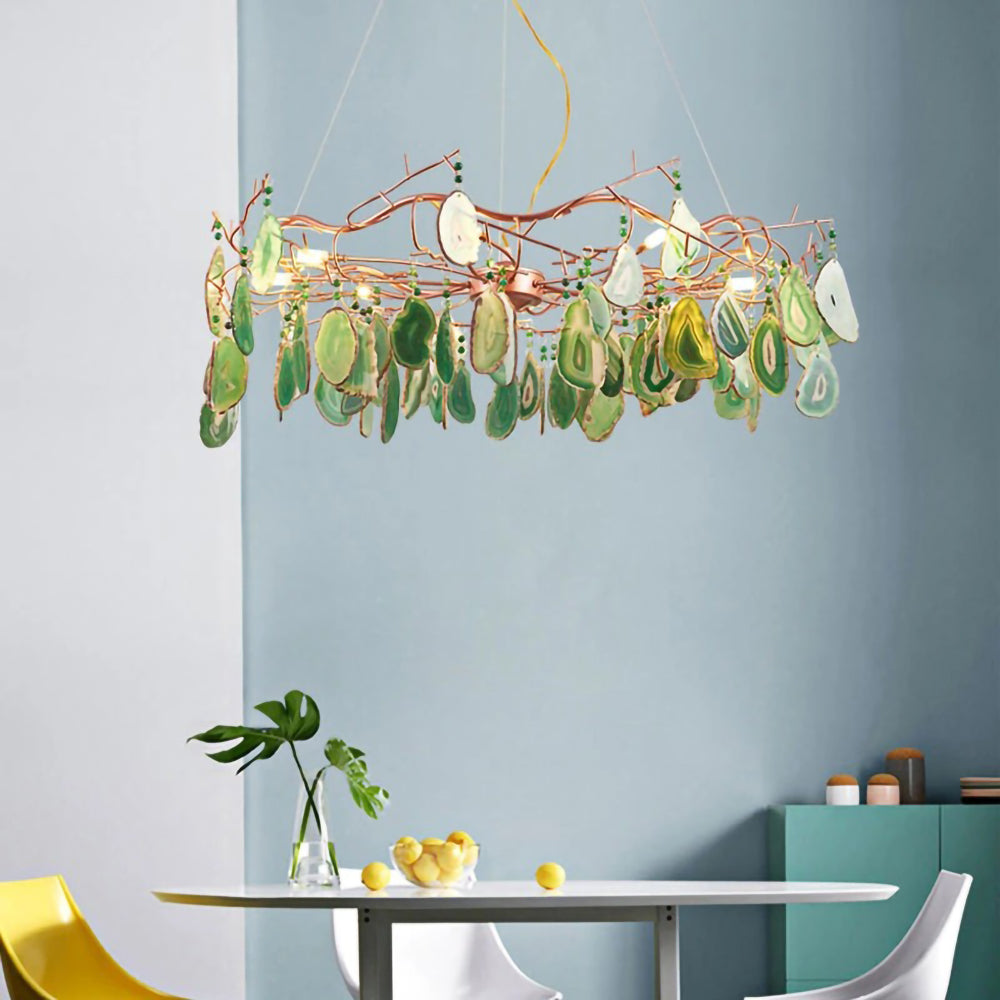 Green-slice Clérachic agate chandelier above a small round table with a lemon bowl, in front of a blue-grey wall.