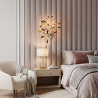 A Clérachic agate wall light glowing above a bedside table, against a pale pink upholstered headboard wall.