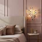 This Clérachic wall light with colourful agate leaves lit beside a bed, against a dusty pink panelled wall.