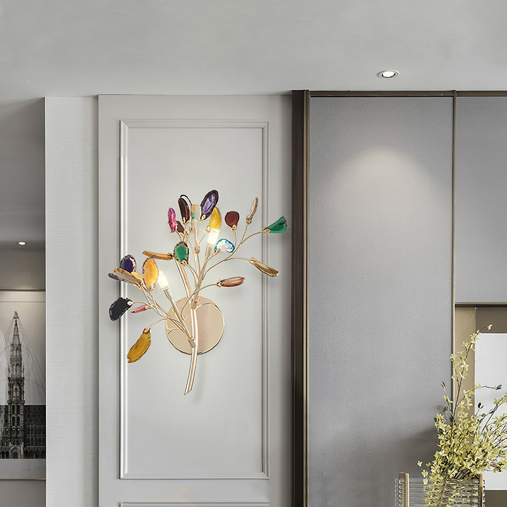 A Clérachic agate wall light mounted on a pale panelled wall, its coloured stone slices catching the glow of the bulbs.
