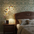 Multicolour Clérachic agate wall light glowing beside a carved wooden bed, on green patterned wallpaper.