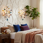 A pair of Clérachic agate wall lights above a bed with blue and purple cushions, beside a tall leafy plant.