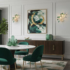 A pair of green Clérachic agate wall lights either side of an abstract painting, above a wood sideboard and a round dining table.