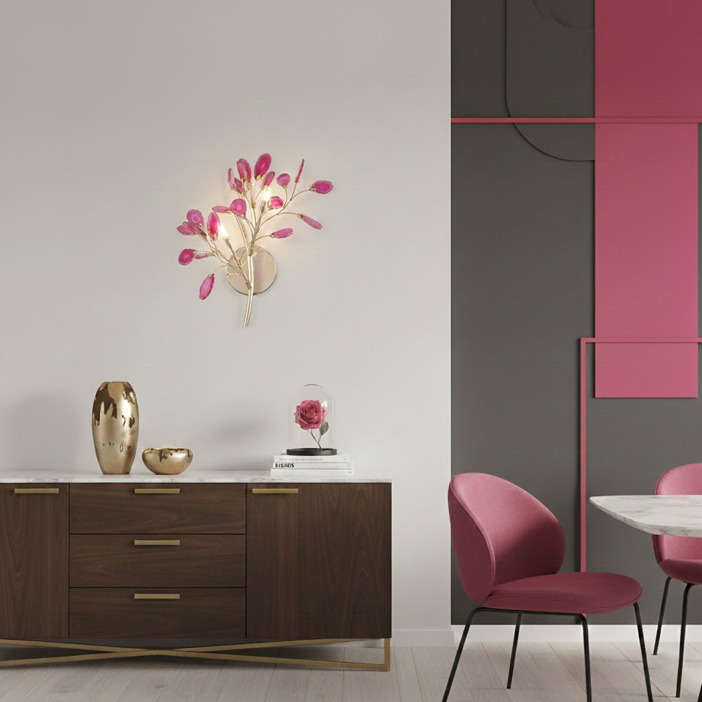 Pink Clérachic agate wall light lit above a wooden chest of drawers, beside a dark panel with a pink stripe.