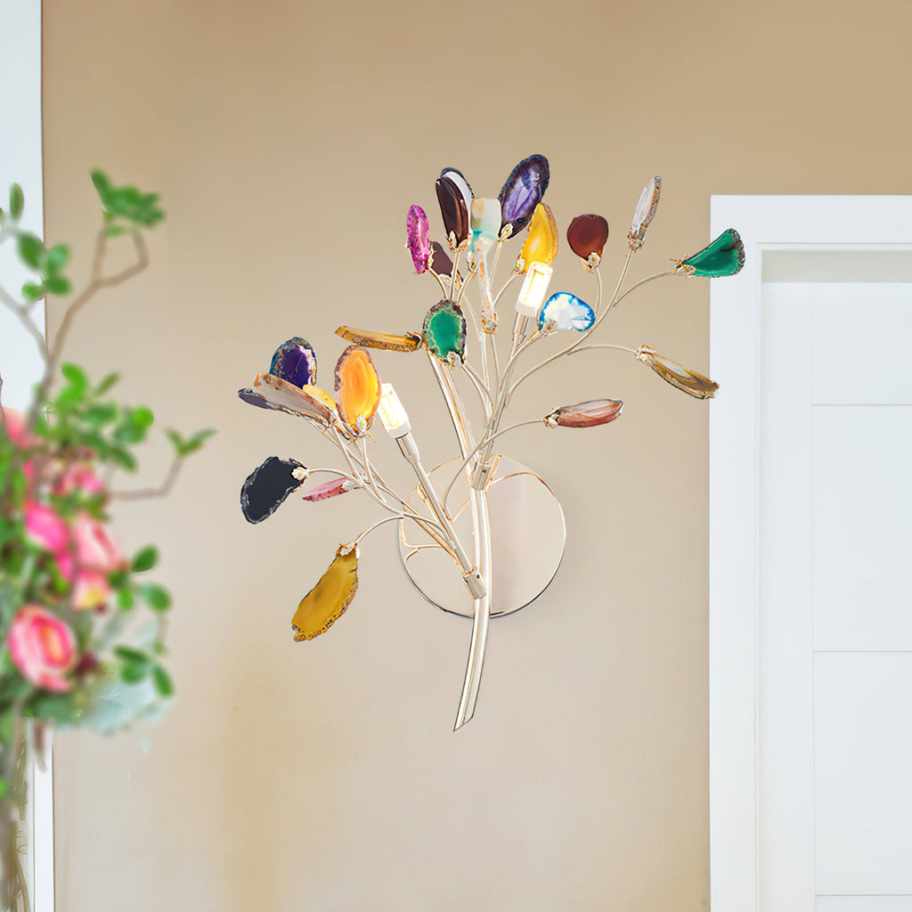 Close view of this Clérachic agate wall light against a warm beige wall, with soft pink flowers blurred at the left.