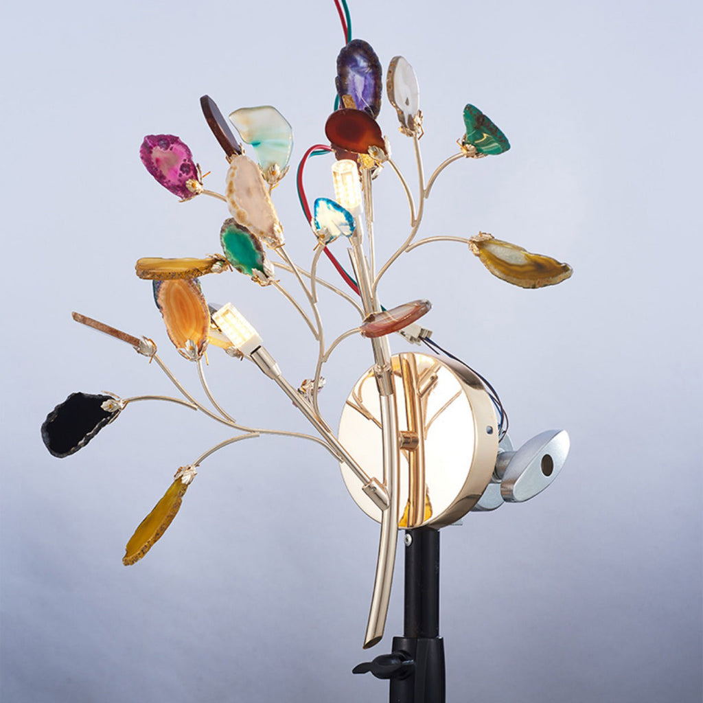 The Clérachic agate wall light photographed on a studio stand against a pale blue backdrop, its wiring visible behind the stems.