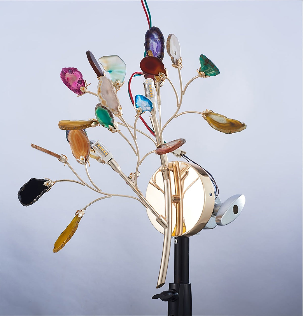 Studio view of the Clérachic agate wall light on a black stand, showing wires and fittings behind the gold stems.