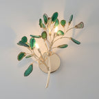 Green Clérachic agate wall light lit on a grey wall, its slices in several shades of green around three small bulbs.