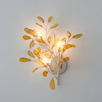 Larger Clérachic agate wall light in yellow and amber stone, lit with four candle-style bulbs on a grey wall.