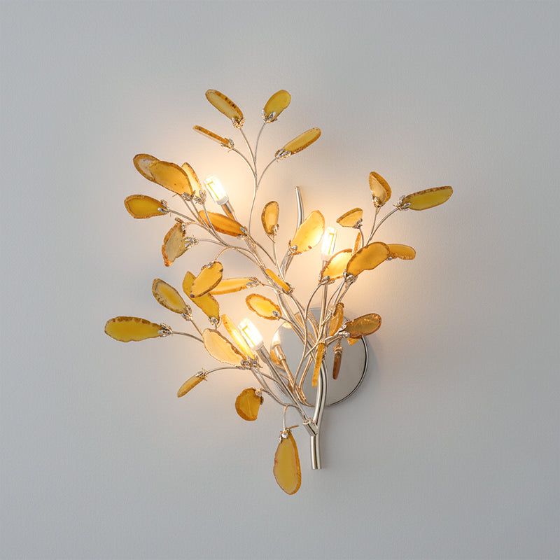 Larger Clérachic agate wall light in yellow and amber stone, lit with four candle-style bulbs on a grey wall.