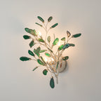 Larger green Clérachic agate wall light lit on a pale wall, with dark green slices around four candle-style bulbs.
