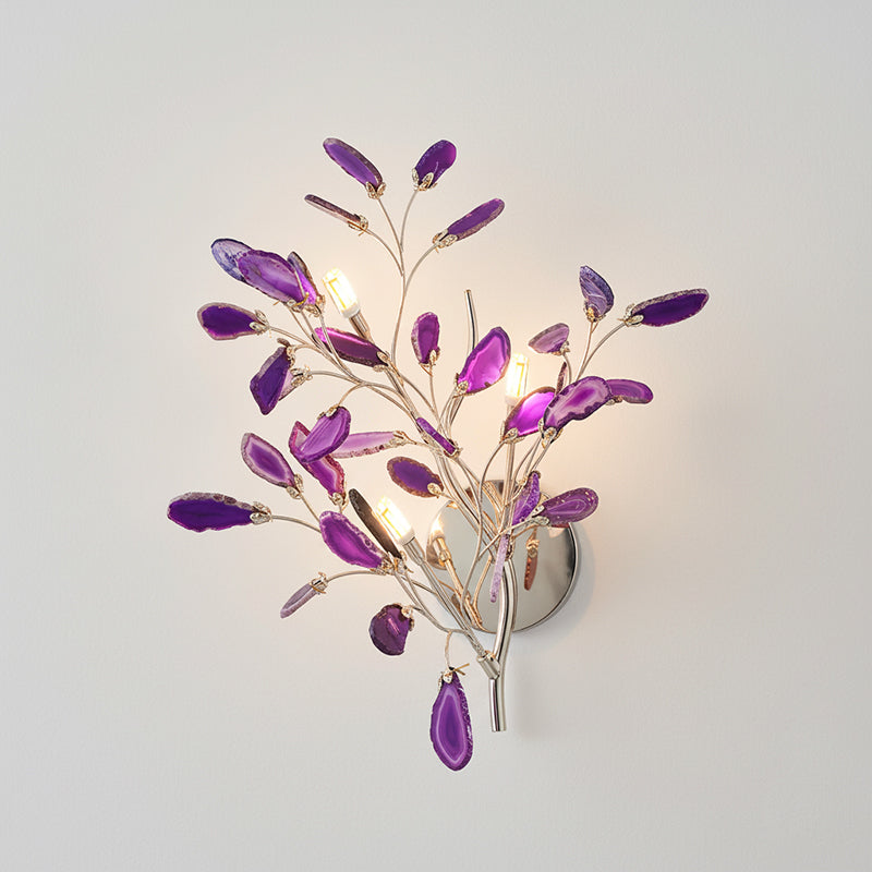 Larger purple Clérachic agate wall light lit on a pale wall, with violet slices around candle-style bulbs.