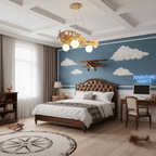 Wooden airplane ceiling light from Clérachic above a boy's bed with a brown headboard, a blue cloud-painted wall and toy biplanes.