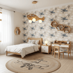 Clérachic airplane ceiling light above a child's bed, with grey plane-patterned wallpaper, hexagonal wooden shelves and a round woven rug.