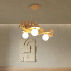 Close view of the Clérachic wooden airplane light, its three globes glowing, against a taupe wall with a textured relief panel.
