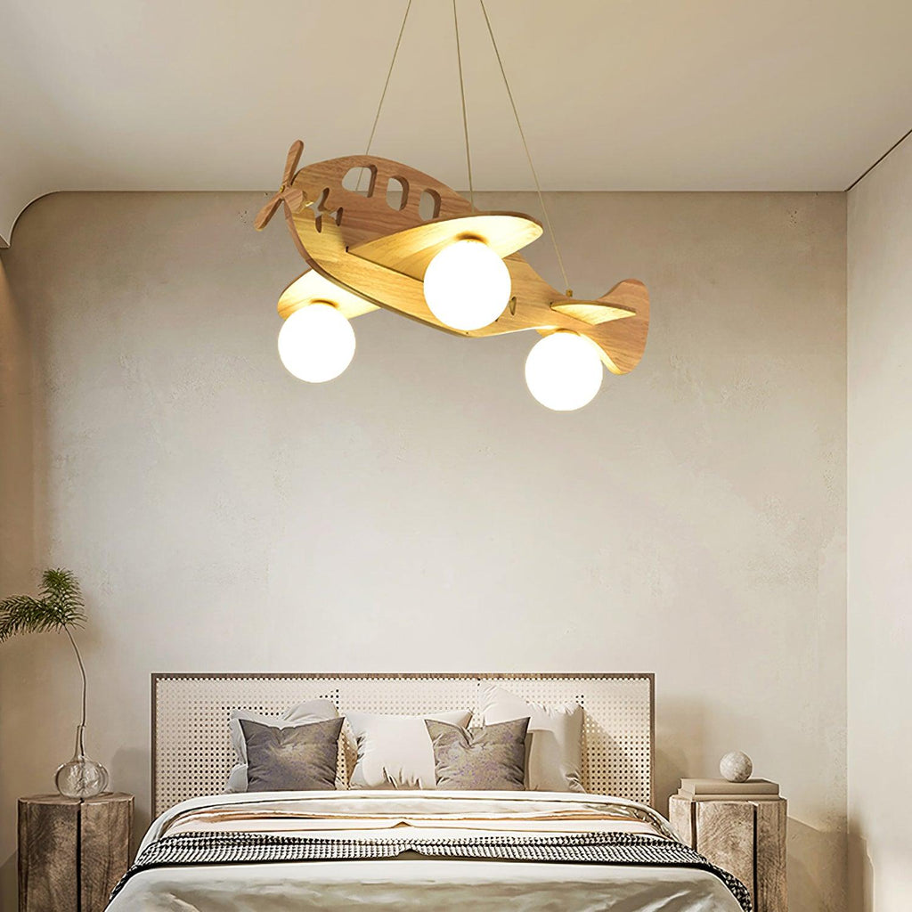 Lit Clérachic airplane pendant over a double bed with a rattan headboard, grey cushions and a striped throw.