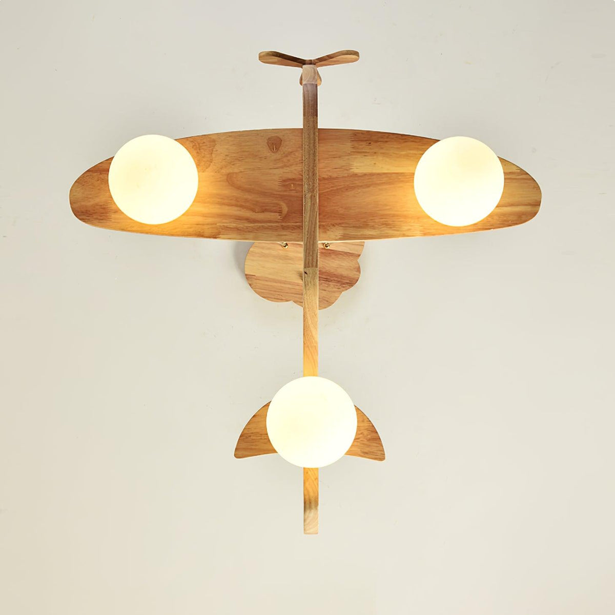View from below of the Clérachic airplane light, showing its wooden wings, tail and propeller with a round white globe under each wing.