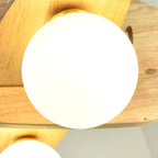 Close view of one frosted white glass globe, lit warm, set beneath the wooden wing of this Clérachic airplane light.