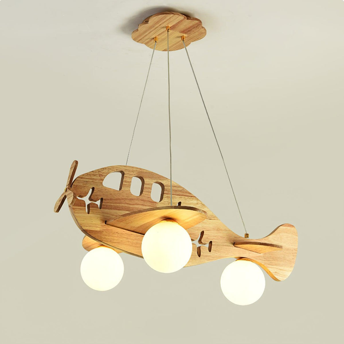 Larger view of the lit Clérachic airplane pendant on a beige backdrop, showing the star-shaped cut-outs along its wooden body.