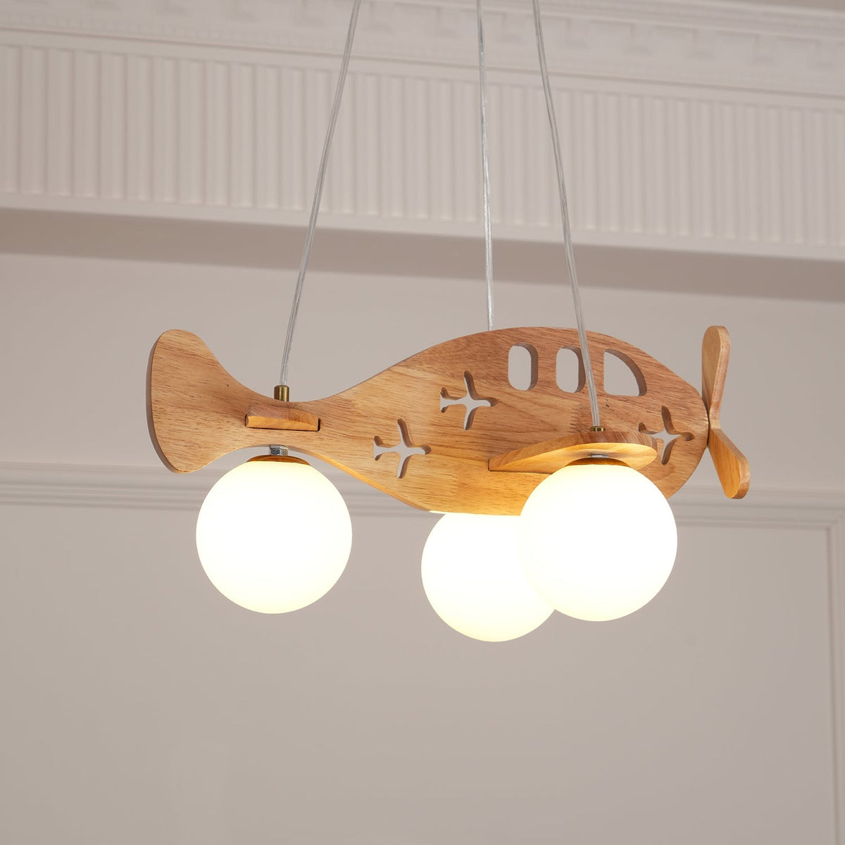 Close view from below of the Clérachic airplane light, the lit globes hanging beneath its wooden wings and cut-out windows.