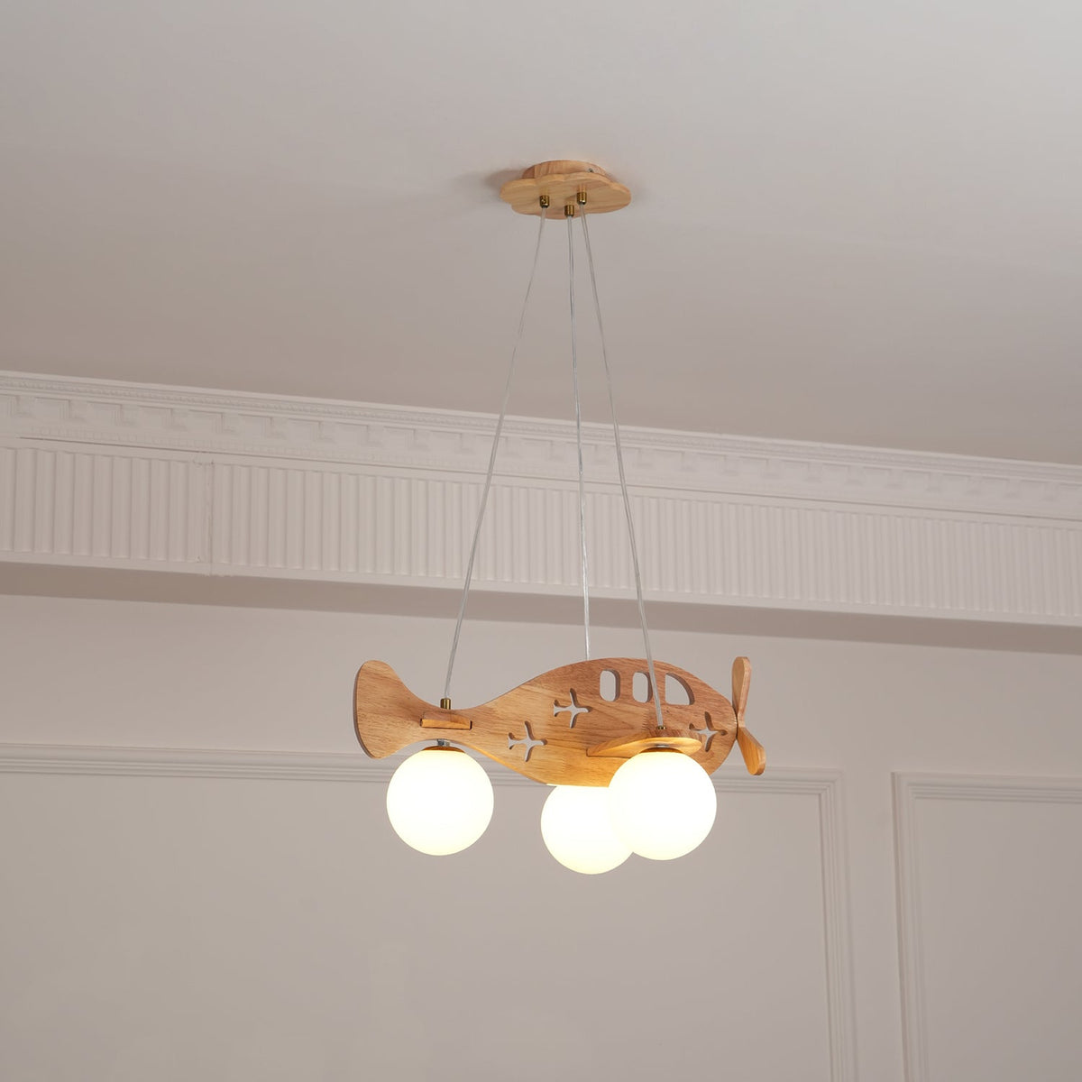 Clérachic wooden airplane pendant hung in the middle of a panelled room, with its cloud-shaped canopy and wires above.
