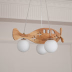 Close view of the Clérachic airplane light from below, with three unlit white globes and the cut-out windows on its wooden body.